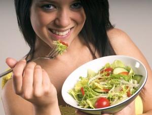 Young woman stood with a bowl of mixed salad containing iceberg lettuce,cherry tomatoes,cucumber,frisee,radish and sliced red peppers.